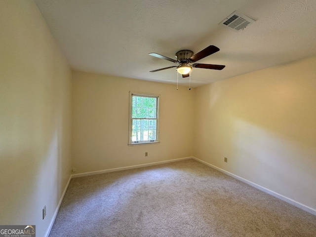 carpeted spare room with a ceiling fan and baseboards