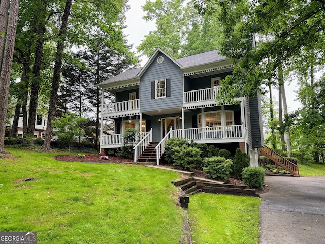 view of front facade featuring covered porch, stairway, and a front yard