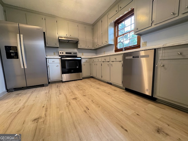 kitchen with stainless steel appliances, gray cabinetry, under cabinet range hood, light wood-type flooring, and light countertops