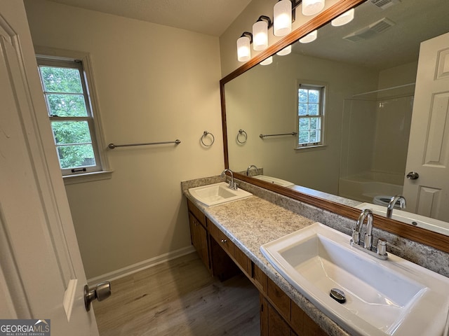 bathroom with wood finished floors, plenty of natural light, double vanity, and baseboards