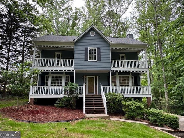 view of front of house featuring a balcony, a chimney, a porch, and stairway