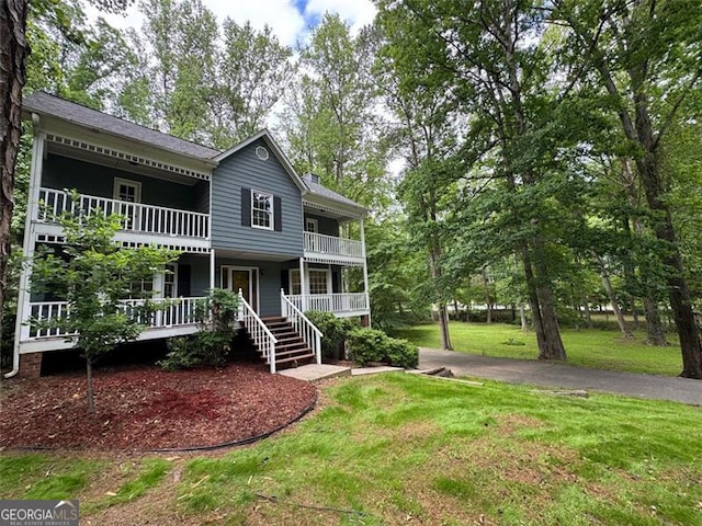 view of front facade with a balcony, a front yard, and a porch