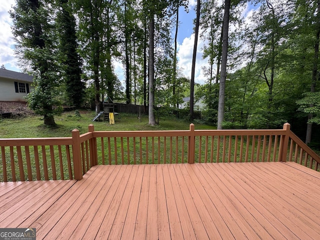 wooden deck featuring a playground and a lawn