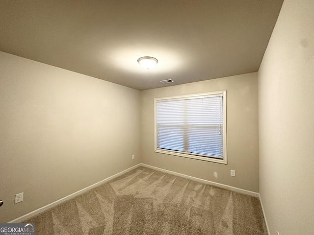 spare room with carpet flooring, visible vents, and baseboards