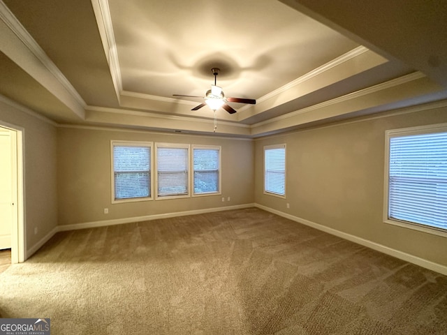unfurnished room featuring a raised ceiling, carpet flooring, baseboards, and a ceiling fan