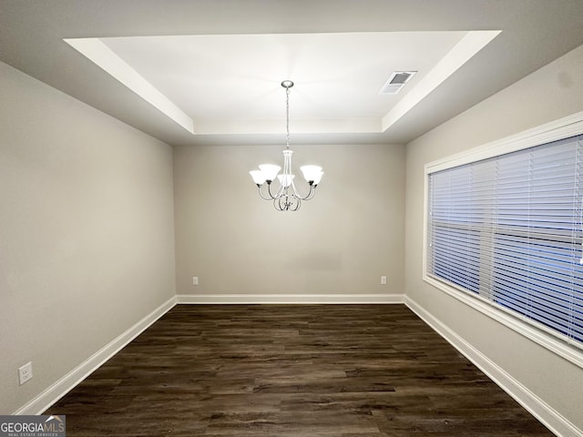unfurnished dining area featuring an inviting chandelier, dark wood finished floors, visible vents, and a raised ceiling