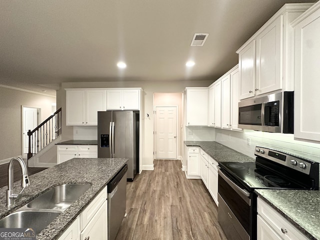 kitchen featuring visible vents, a sink, wood finished floors, white cabinets, and appliances with stainless steel finishes