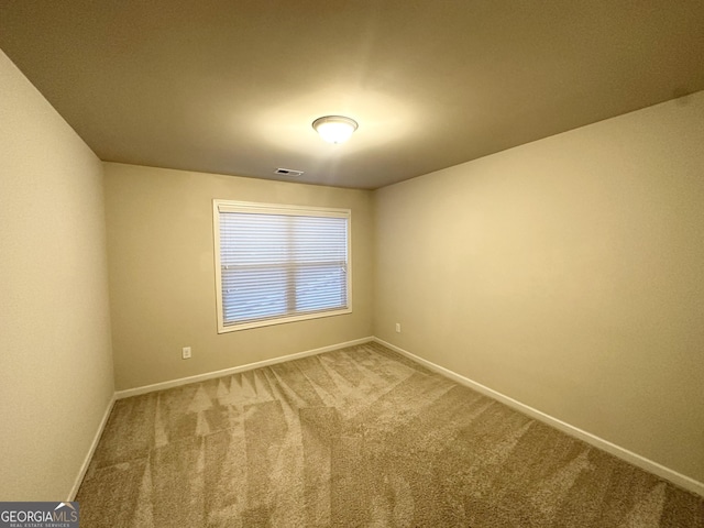 carpeted spare room featuring baseboards and visible vents