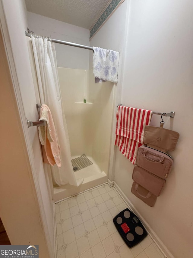 bathroom with a stall shower, baseboards, and a textured ceiling