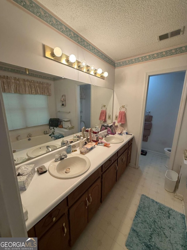 bathroom with toilet, a sink, tile patterned floors, a textured ceiling, and visible vents