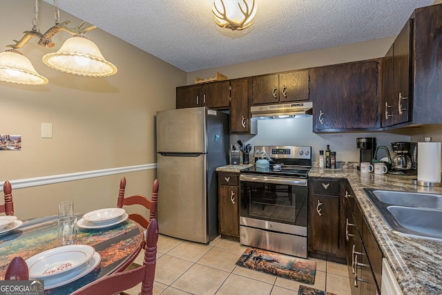 kitchen featuring a sink, a textured ceiling, under cabinet range hood, light tile patterned floors, and appliances with stainless steel finishes