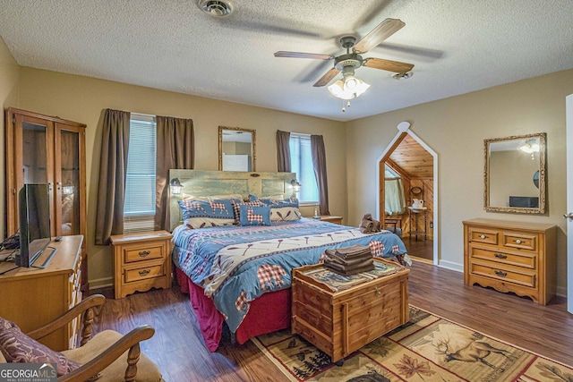bedroom featuring a textured ceiling, baseboards, visible vents, and wood finished floors