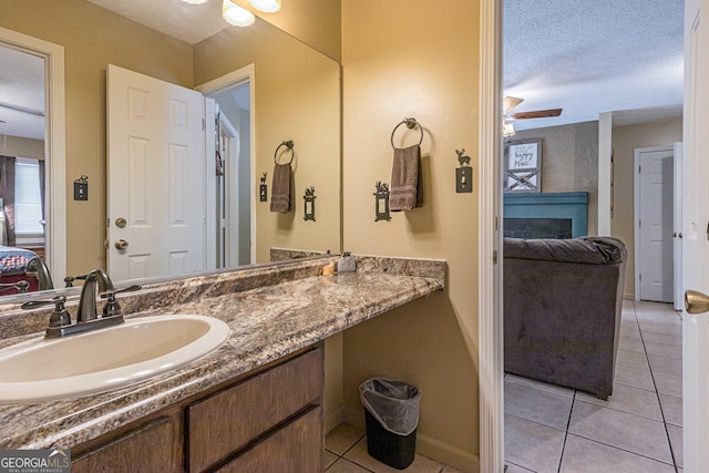 bathroom with a ceiling fan, a textured ceiling, baseboards, ensuite bathroom, and tile patterned floors