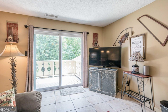 living room featuring a textured ceiling, visible vents, and tile patterned flooring