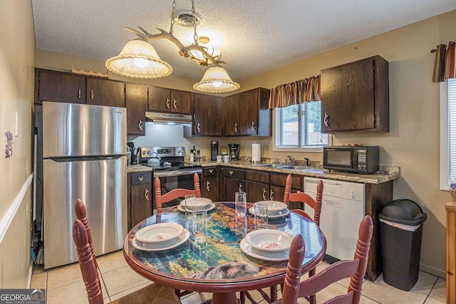 kitchen featuring light tile patterned floors, appliances with stainless steel finishes, under cabinet range hood, and dark brown cabinetry
