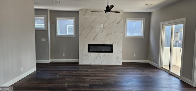 unfurnished living room featuring a ceiling fan, baseboards, a high end fireplace, and dark wood-style floors