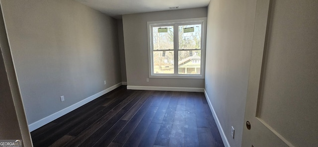 spare room featuring baseboards, visible vents, and dark wood-style floors