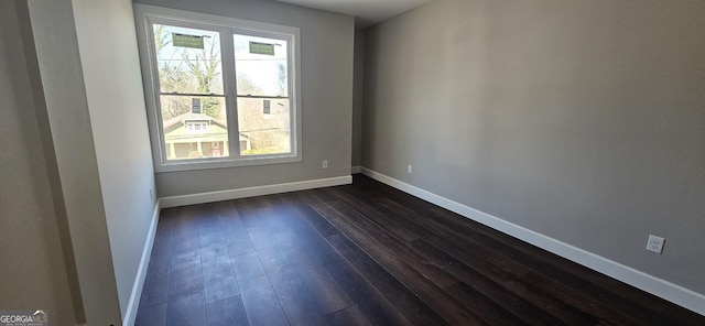 spare room featuring baseboards, a healthy amount of sunlight, and dark wood-style floors