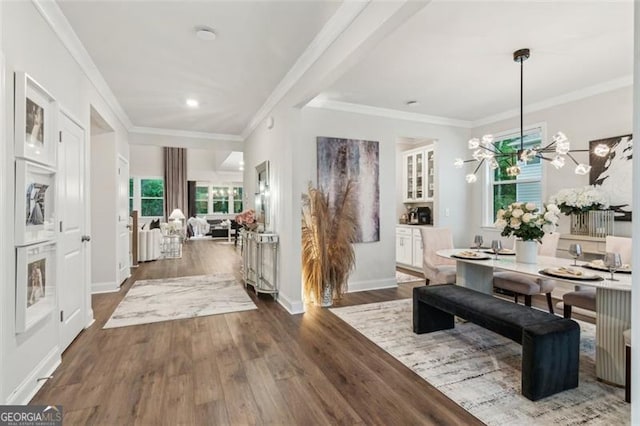 corridor featuring wood finished floors, ornamental molding, a chandelier, baseboards, and recessed lighting