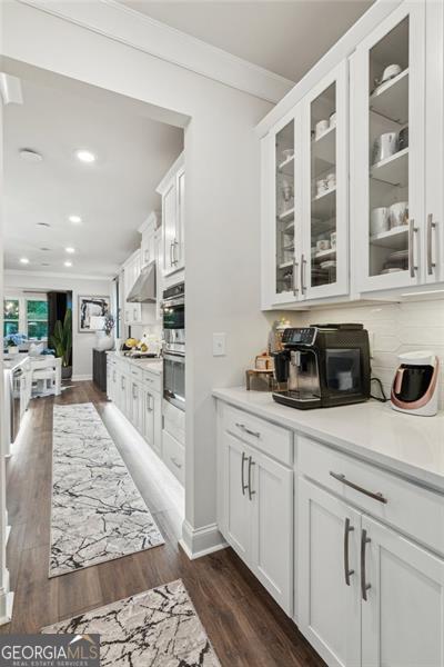 bar area featuring crown molding, recessed lighting, dark wood finished floors, backsplash, and under cabinet range hood