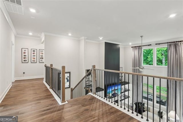 hallway featuring an upstairs landing, recessed lighting, wood finished floors, crown molding, and baseboards