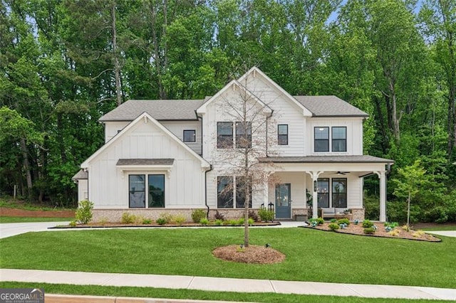 view of front of house featuring board and batten siding, a porch, a front yard, and stone siding