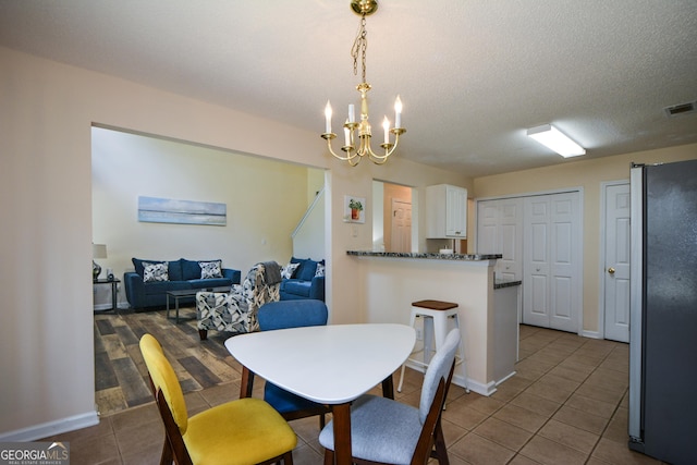 dining area featuring tile patterned flooring, a chandelier, and baseboards