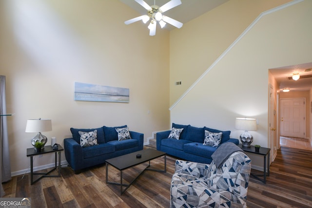 living area with wood finished floors, a ceiling fan, a high ceiling, and baseboards
