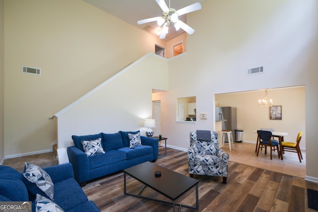 living room with a high ceiling, a chandelier, wood finished floors, ceiling fan, and baseboards