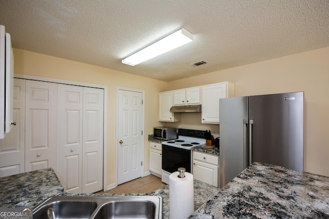 kitchen with appliances with stainless steel finishes, under cabinet range hood, white cabinetry, light tile patterned floors, and a textured ceiling