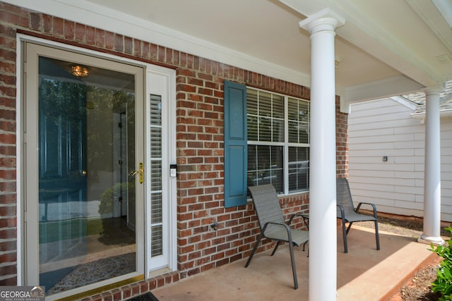 property entrance featuring a porch and brick siding