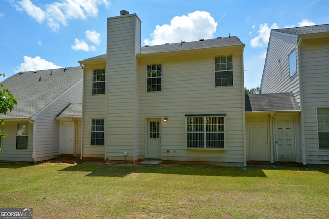 back of property featuring a chimney and a lawn