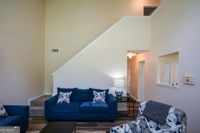 living room with a high ceiling, baseboards, and wood finished floors