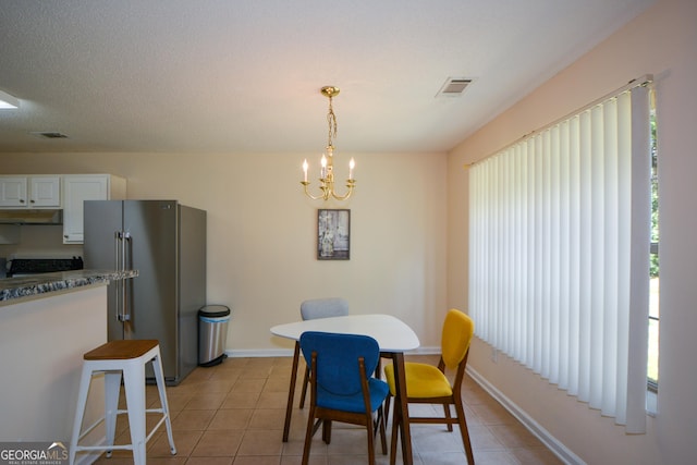dining space with a chandelier, light tile patterned flooring, and baseboards