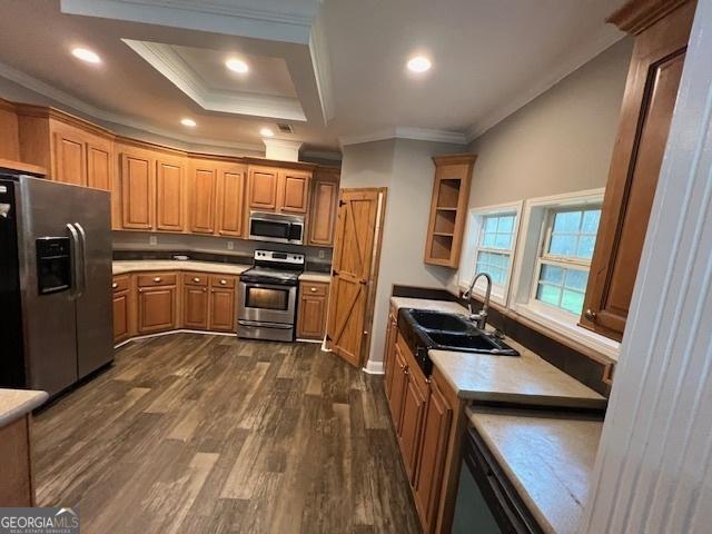kitchen with a sink, stainless steel appliances, ornamental molding, light countertops, and dark wood-style floors