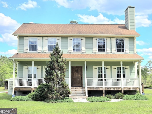view of front of home with a chimney, a porch, and a front lawn
