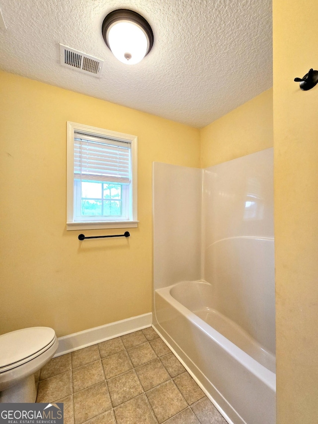 bathroom with toilet, tile patterned floors, a textured ceiling, visible vents, and baseboards