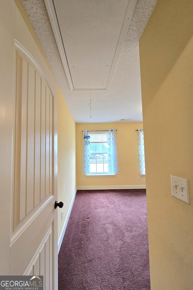 empty room with attic access, baseboards, and carpet