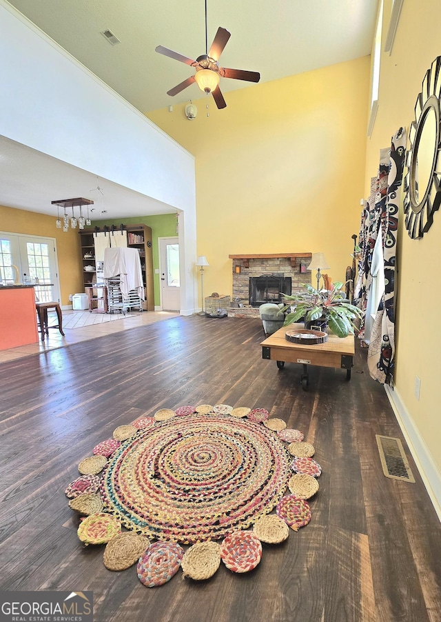 living area featuring ceiling fan, a fireplace, visible vents, and wood finished floors