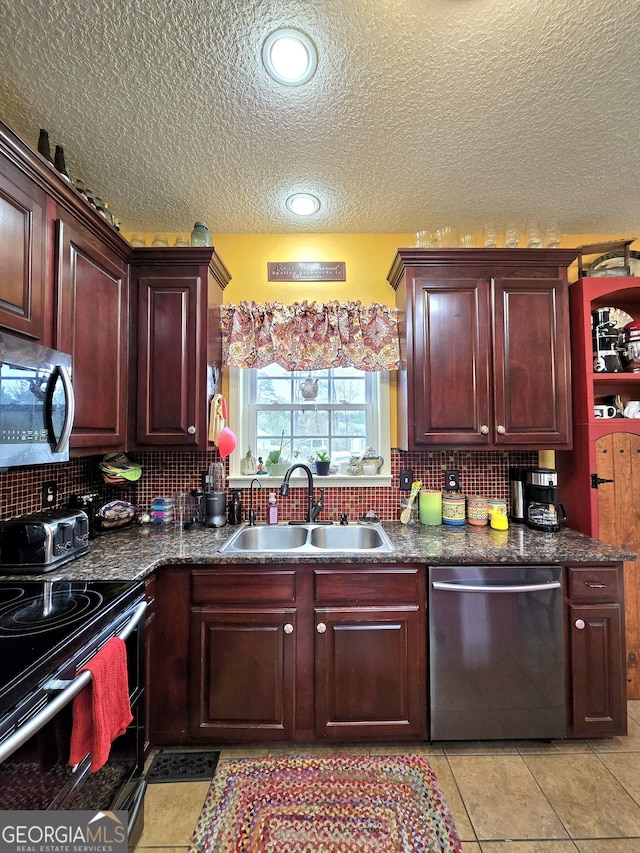 kitchen featuring a sink, stainless steel appliances, tasteful backsplash, a textured ceiling, and dark countertops