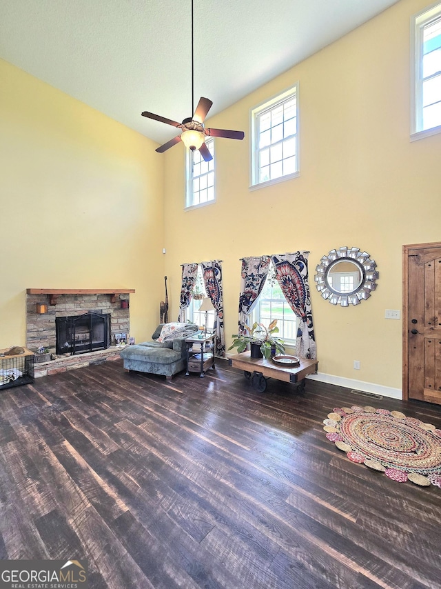living room featuring a ceiling fan, a healthy amount of sunlight, a towering ceiling, and wood finished floors