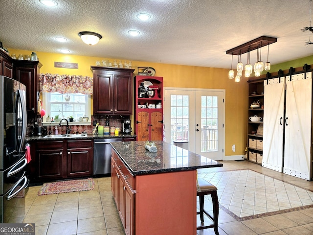 kitchen featuring light tile patterned floors, a sink, freestanding refrigerator, backsplash, and dishwasher