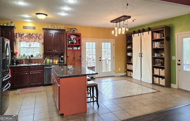 kitchen featuring a sink, a breakfast bar, freestanding refrigerator, dishwasher, and a kitchen island