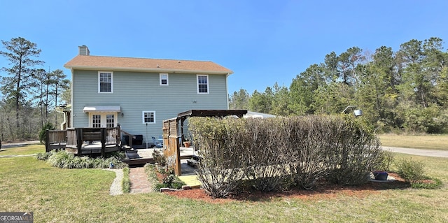 rear view of house featuring a yard, a chimney, and a deck