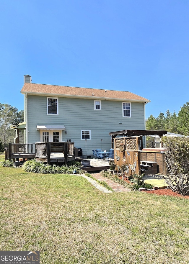 rear view of property featuring a yard, a wooden deck, and a chimney