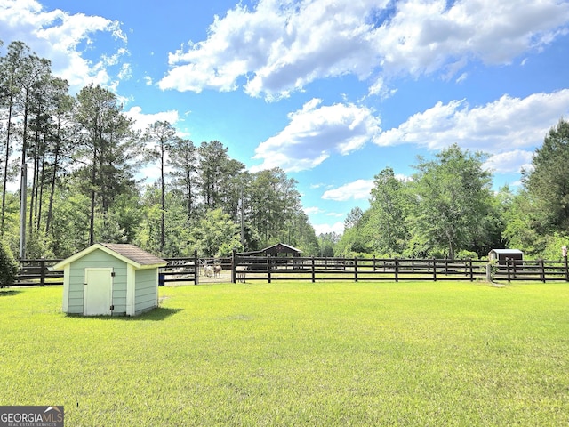 view of yard with a storage unit, fence, and an outbuilding