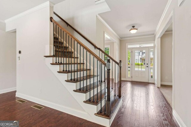 entryway featuring crown molding, wood finished floors, baseboards, and stairs