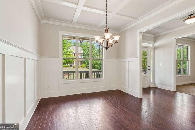 unfurnished dining area with a decorative wall, dark wood-style flooring, a chandelier, coffered ceiling, and a wainscoted wall