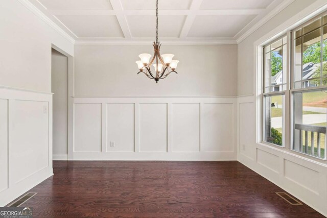 unfurnished dining area with a decorative wall, coffered ceiling, a chandelier, dark wood-type flooring, and wainscoting