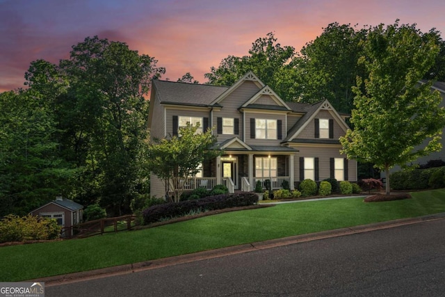 craftsman house with a porch, a lawn, an outdoor structure, and a storage unit